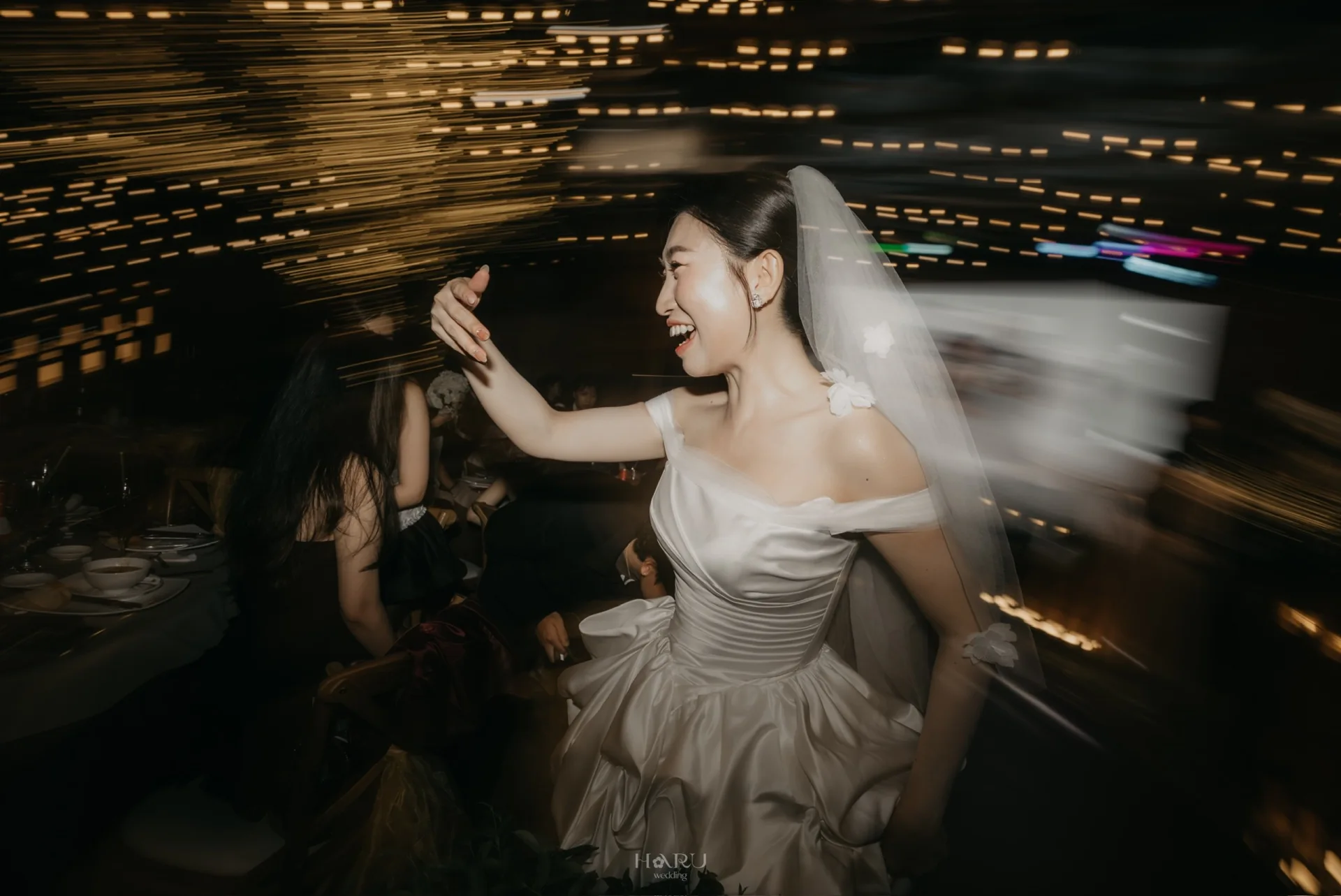 Cô dâu mỉm cười giữa những vệt sáng chuyển động trong tiệc cưới