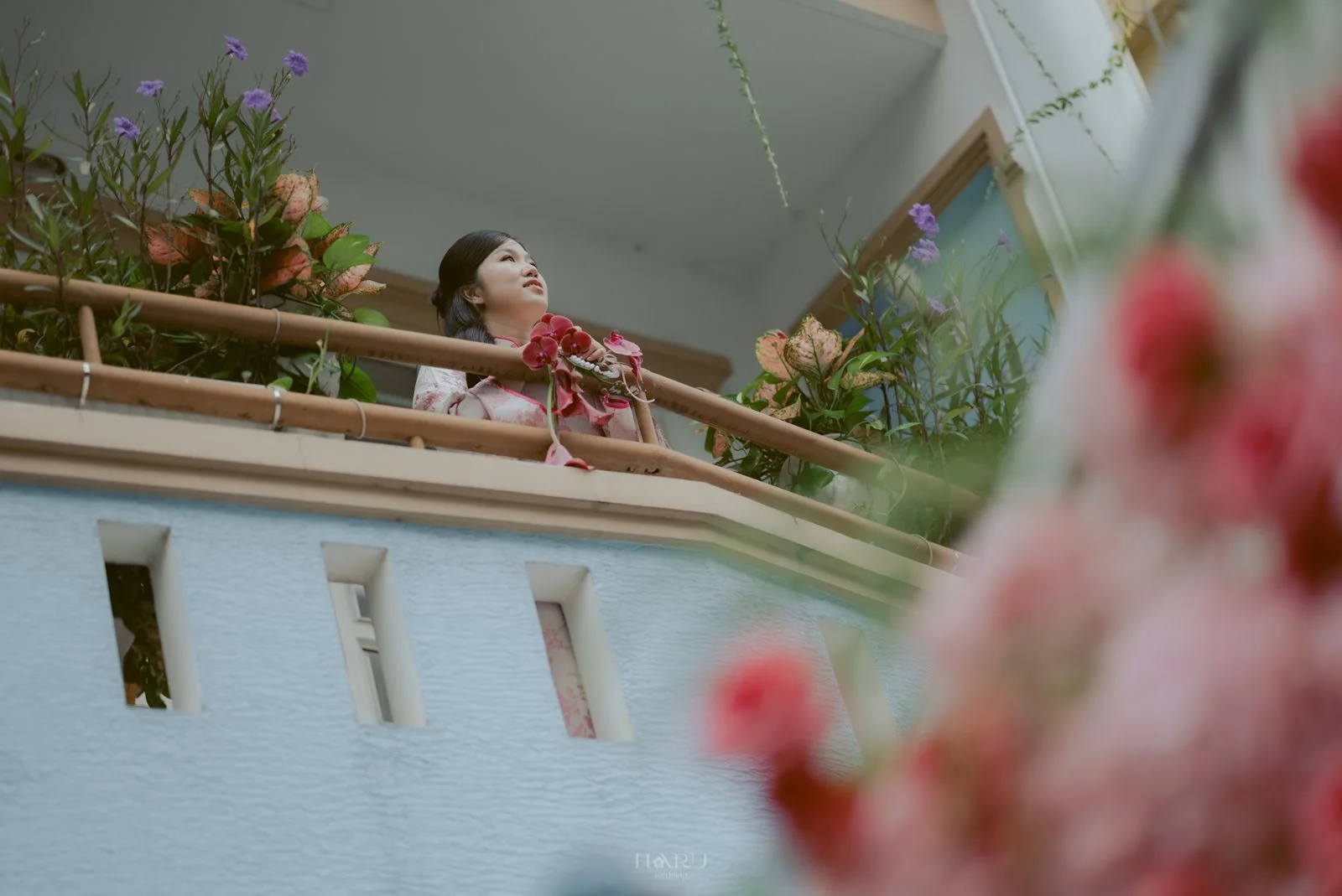 Cô dâu đứng trên ban công giữa hoa ngày cưới